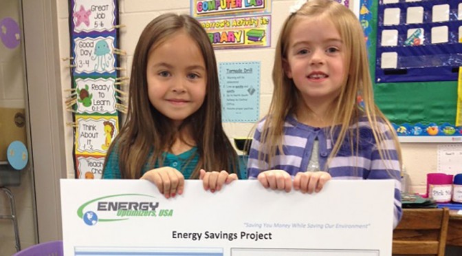 Students holding Energy Savings Project flyer in classroom