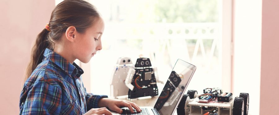 young girl on computer with robotics on desk; STEM robotics team