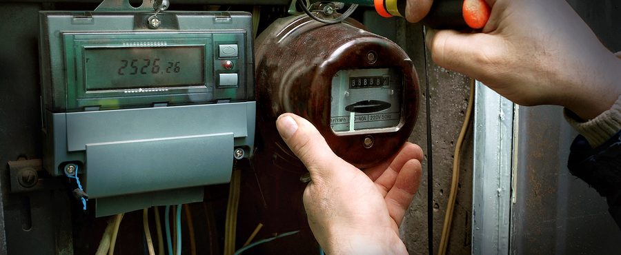 An electrician dismantles the old analog electricity counter, near the installed digital meter.